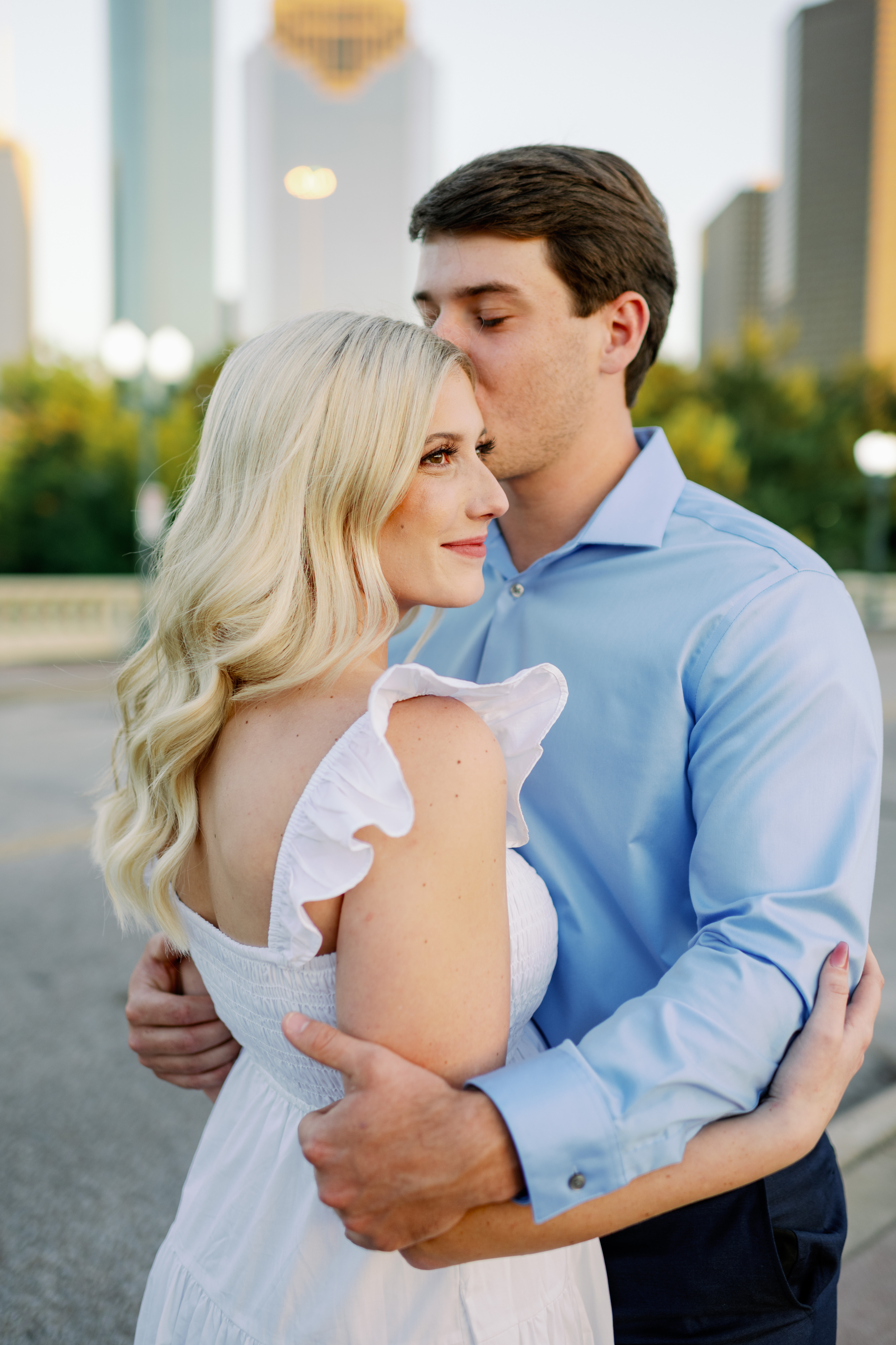 Engaged couple poses in Houston’s Buffalo Bayou Park for a skyline portrait session