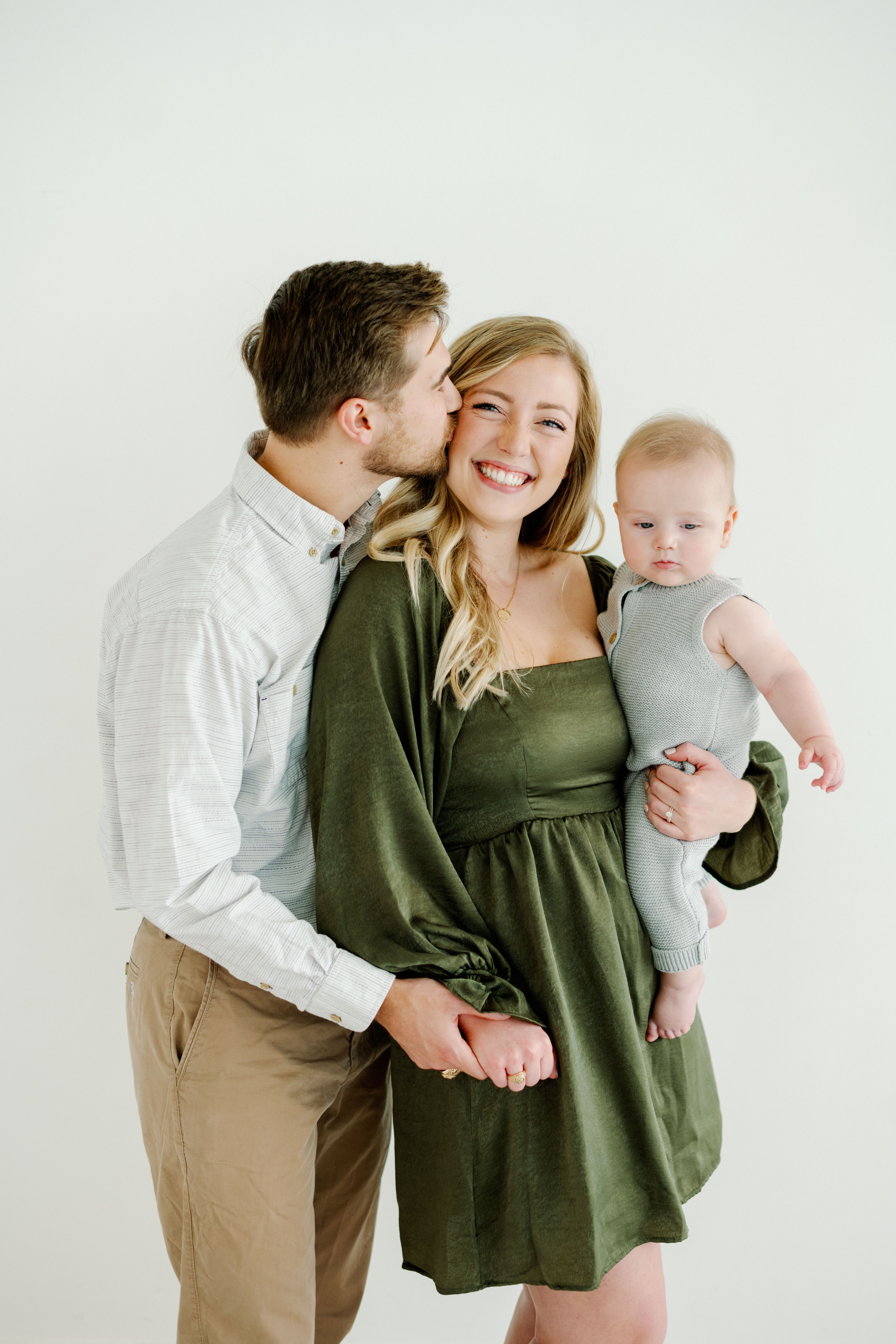 A young family of three pose for a family portrait session in a natural light studio with Kati Hewitt Photography
