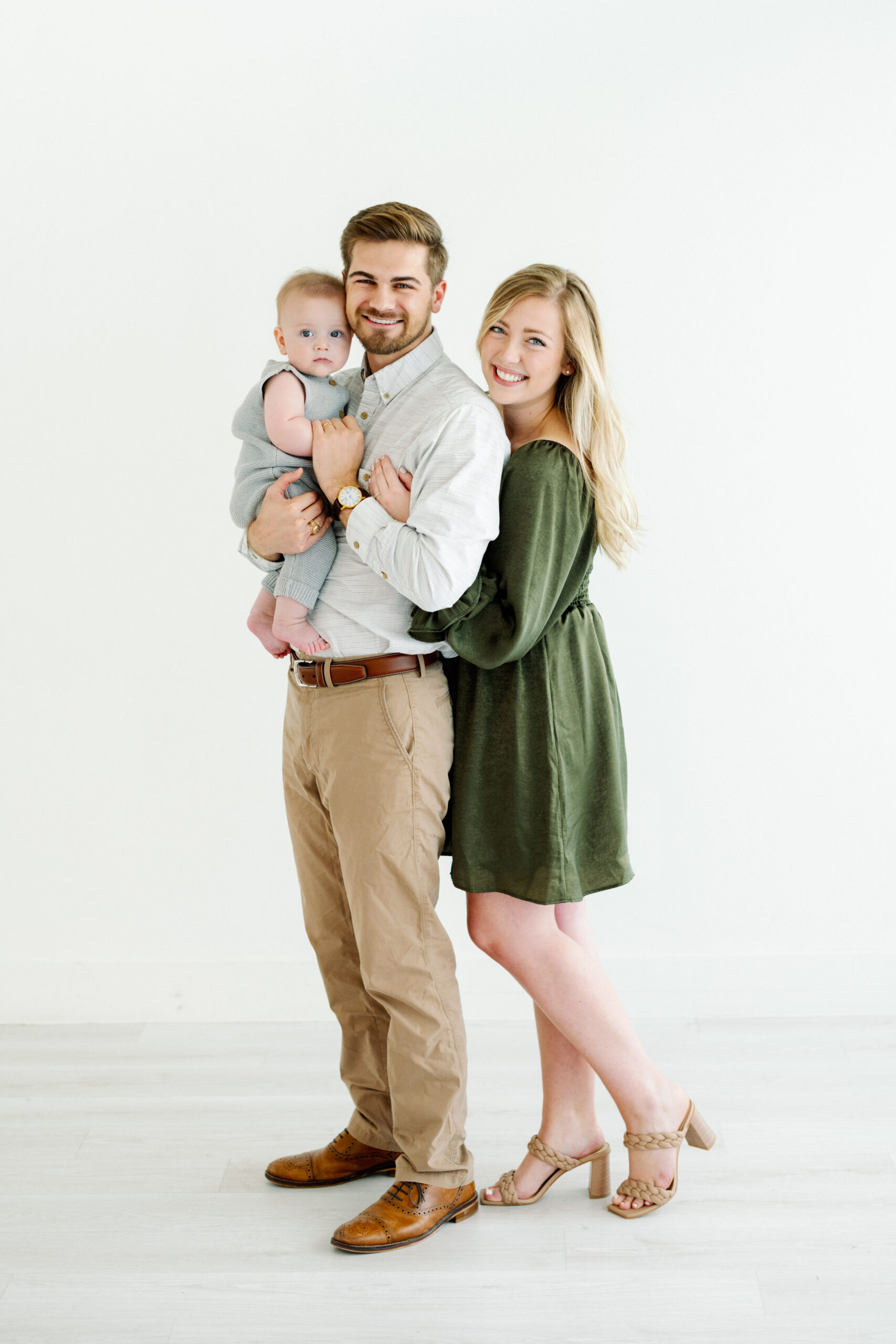A young family of three pose for a family portrait session in a natural light studio with Kati Hewitt Photography