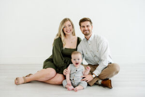 A young family of three pose for a family portrait session in a natural light studio with Kati Hewitt Photography